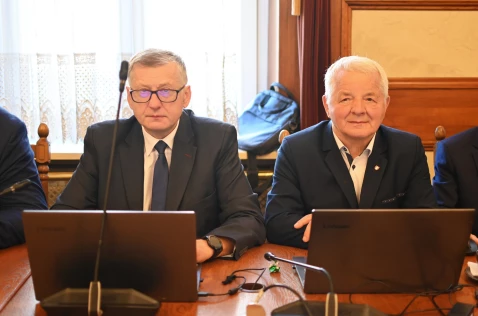 Radni Wojciech Karwat i Leszek Dolny siedzą w sali sesyjnej przy laptopach