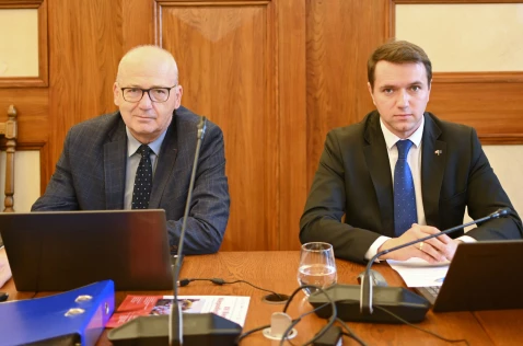 Radni Wojciech Bosak i Piotr Opalski siedzą w sali sesyjnej przy laptopach