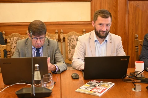 Radni Grzegorz Małodobry i Marian Janicki siedzą w sali sesyjnej przy laptopach