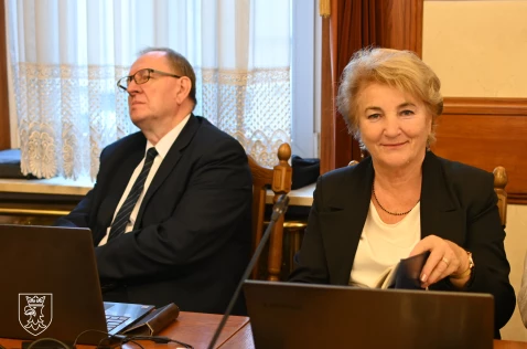 Radny Paweł Kolasa oraz radna Janina Grela siedzą w sali sesyjnej