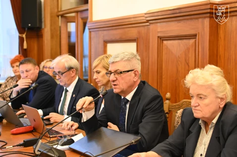 Przemawiający członek Zarządu Tadeusz Nabagło oraz radni Powiatu siedzą na sali sesyjnej