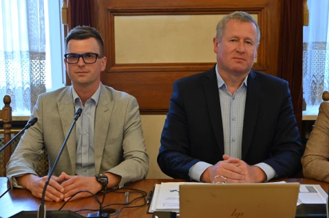Radni Bartłomiej Szwed i Jarosław Raźny przy laptopie siedzą w sali sesyjnej.