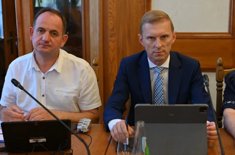 Radni Grzegorz Kowalik i Michał Tochowicz siedzą przy laptopach w sali sesyjnej.