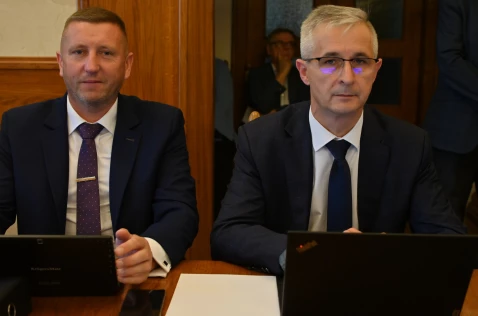 Radny Krzysztof Krupa i członek Zarządu Grzegorz Stokłosa siedzą przy laptopach w sali sesyjnej.
