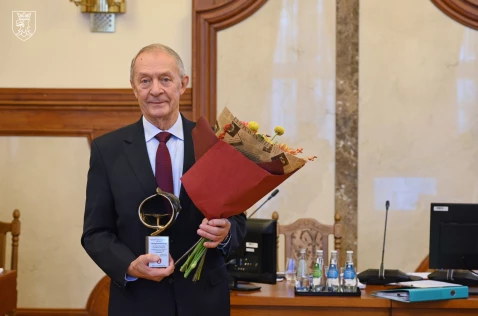 Jerzy Wodnicki stoi zwrócony do obiektywu z odznaczeniem i kwiatami