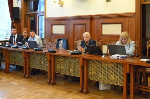 Radni Powiatu i skarbnik siedzą przy biurkach na sali sesyjnej
